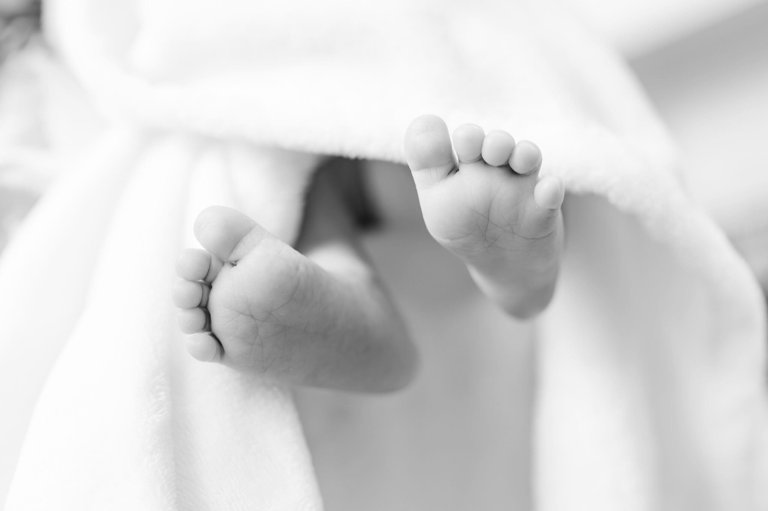 black and white close up of baby feet; benefits of in-home session